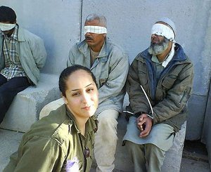 Una soldado del estado terrorista de Israel se fotografía junto a prisioneros